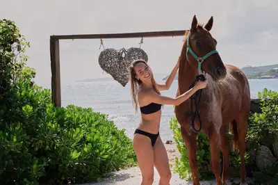 a woman in a bikini standing next to a horse at The Aerial, BVI in Tortola Island