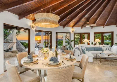 a dining room with a table and a couch at On The Rocks Villa in Spanish Town
