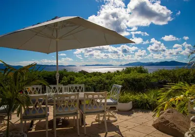 a table and chairs with an umbrella and water at On The Rocks Villa in Spanish Town