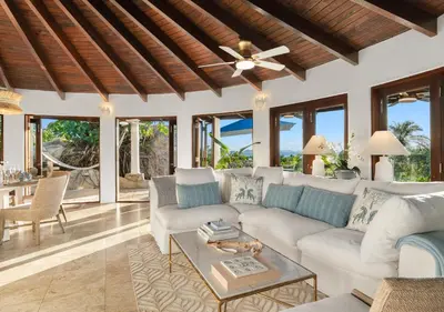 a living room with a white couch and a ceiling fan at On The Rocks Villa in Spanish Town