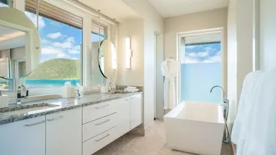 a white bathroom with a sink and a large window at Oil Nut Bay in Virgin Gorda