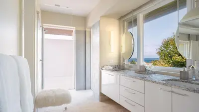 a white bathroom with a large window and a sink at Oil Nut Bay in Virgin Gorda