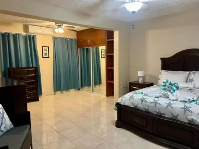 a bedroom with a bed and a dresser and a mirror at Ocean Breeze Comfort in East End