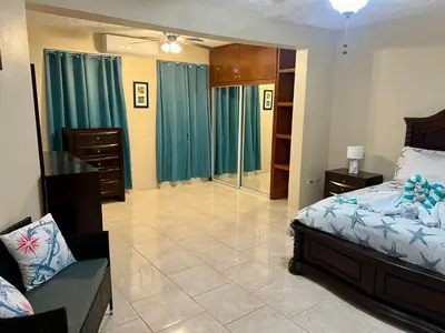 a bedroom with a bed and a chair in it at Ocean Breeze Comfort in East End