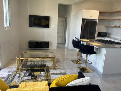 a living room with a glass table and a kitchen at Exquisitely Threadfall in Cane Garden Bay