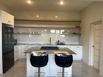a kitchen with white cabinets and a counter with black stools at Exquisitely Threadfall in Cane Garden Bay