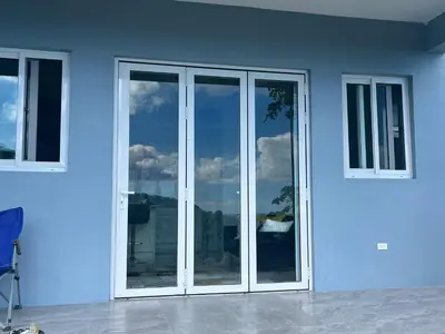 a white building with glass doors and windows at Exquisitely Threadfall in Cane Garden Bay