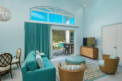 a living room with a couch and chairs and a television at Cane Garden Bay Beach Hotel in Cane Garden Bay