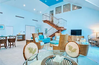 a living room with a spiral staircase and furniture at Cane Garden Bay Beach Hotel in Cane Garden Bay