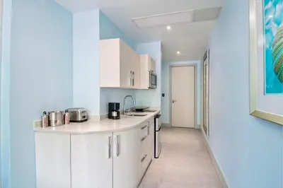 a kitchen with white cabinets and blue walls at Cane Garden Bay Beach Hotel in Cane Garden Bay