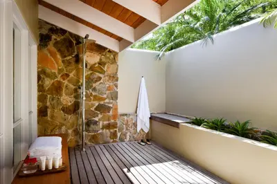 a balcony with a shower and a stone wall at Rosewood Little Dix Bay in Virgin Gorda Airport