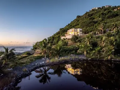 a house on top of a hill next to the ocean at Cannon Point Estate in Cane Garden Bay