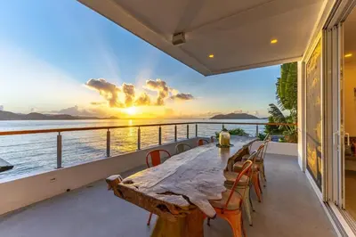 a dining table on a balcony with a view of the ocean at Cannon Point Estate in Cane Garden Bay