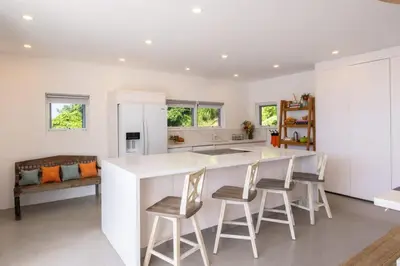 a kitchen with a large white counter and chairs at Cannon Point Estate in Cane Garden Bay