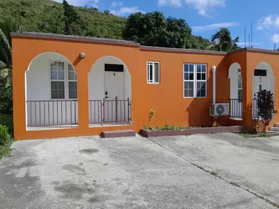 an orange house with white doors and a driveway at Abigail Diamond 1 Bedroom near Nanny Cay Marina in Tortola Island