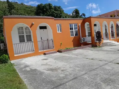 an orange house with white doors and a driveway at Abigail Diamond 1 Bedroom near Nanny Cay Marina in Tortola Island