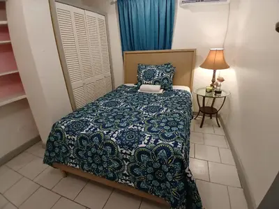 a small bedroom with a bed and a table at Beach Front Haven, by More Than Beauty Properties in Tortola Island