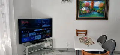 a living room with a tv and a table with chairs at Beach Front Haven, by More Than Beauty Properties in Tortola Island
