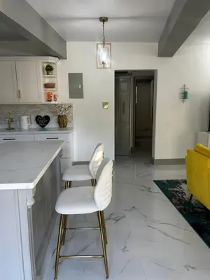 a kitchen with two white chairs and a counter at Cane Garden Bay 2 bed Apt in Leonards