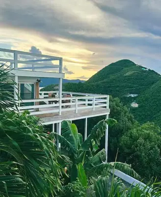 a building with a balcony with a mountain in the background at Solace Villa in Little Carrot Bay