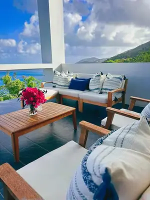 a balcony with a couch and a table with flowers at Solace Villa in Little Carrot Bay