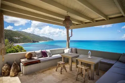 a patio with a couch and a view of the ocean at House of Rogues in Tortola Island