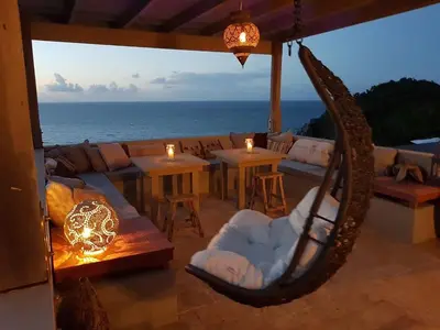 a living room with a couch and tables and the ocean at House of Rogues in Tortola Island
