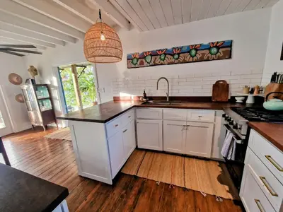 a kitchen with white cabinets and a black counter top at Lowena Cottage in Tortola Island