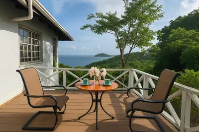 a wooden deck with two chairs and a table with flowers on it at BluEdge Villa VIP Resort Access in Tortola Island