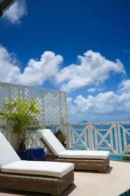 a pair of lounge chairs on a patio with the ocean at Endless Summer Villa in Tortola Island