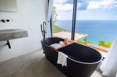 a black bath tub in a bathroom with a view of the ocean at Villa Odyssea BVI in Tortola Island