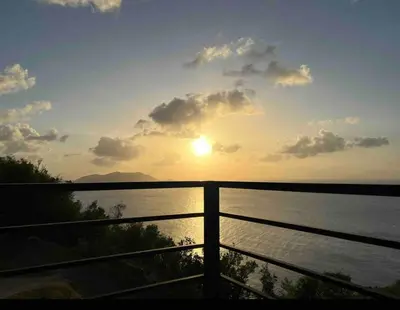 a sunset over a body of water with a fence at Villa Modere' in Tortola Island