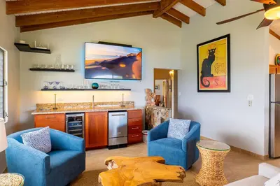 a living room with two blue chairs and a kitchen at Tamarind Villa in Virgin Gorda