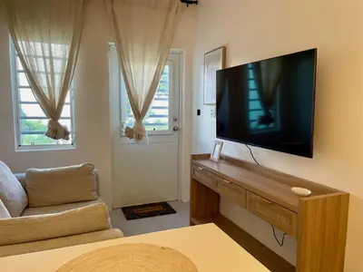 a living room with a flat screen tv on a wall at Abigail's Sunlit Nook in Tortola Island