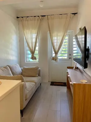 a living room with a couch and two windows at Abigail's Sunlit Nook in Tortola Island