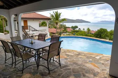 a patio with a table and chairs next to a swimming pool at Villa ValMarc Mahoe Bay Virgin Gorda BVI in Virgin Gorda