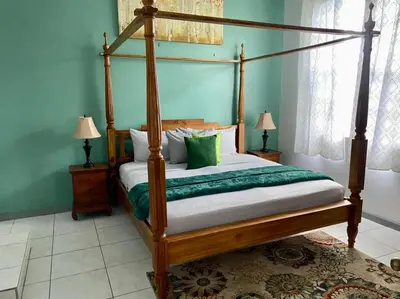 a bedroom with a wooden canopy bed with green pillows at Tranquil Escape at Ballast Bay in Road Town