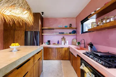 a kitchen with pink walls and wooden cabinets at Odyssea Oasis in Tortola Island