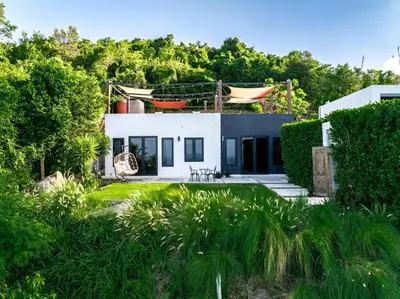a white house with a garden and trees at Odyssea Oasis in Tortola Island
