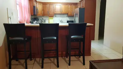 a kitchen with black chairs at a kitchen counter at SUNFLOWER LANE QUEEN Balcony Room APARTMENT in Tortola Island