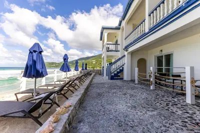 a row of chairs and umbrellas next to a building at Sebastian's on the beach hotel in Road Town
