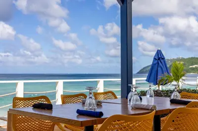 a table with chairs and a view of the ocean at Sebastian's on the beach hotel in Road Town