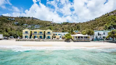 a group of houses on a beach next to the ocean at Sebastian's on the beach hotel in Road Town