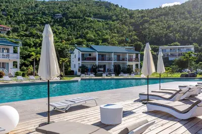a pool at a resort with chairs and umbrellas at Wyndham Tortola BVI Lambert Beach Resort in East End