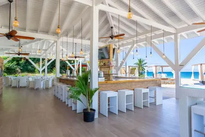 a restaurant with white tables and white chairs at Wyndham Tortola BVI Lambert Beach Resort in East End