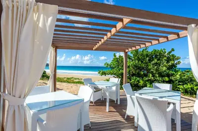 a wooden deck with tables and chairs on the beach at Wyndham Tortola BVI Lambert Beach Resort in East End