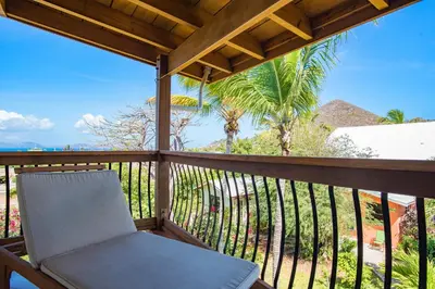 a chair on a balcony with palm trees at Bayview Vacation Apartments in Virgin Gorda