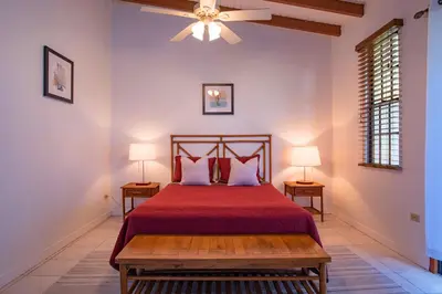 a bedroom with a bed with a red bedspread and two lamps at Bayview Vacation Apartments in Virgin Gorda