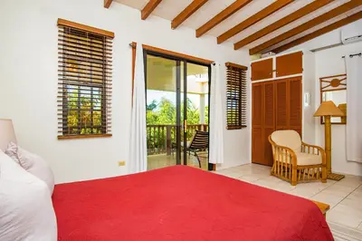 a bedroom with a red bed and a balcony at Bayview Vacation Apartments in Virgin Gorda
