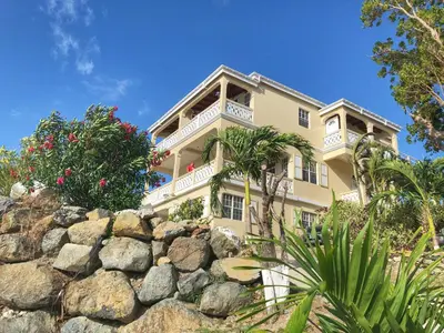 a building behind a rock wall at Ocean View Villas in Jost Van Dyke